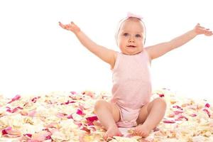 Cute baby girl sitting surrounded rose petals photo