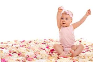 Cute baby girl sitting surrounded rose petals photo