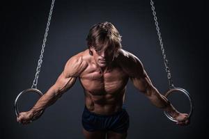 gimnasta fuerte y musculoso en los anillos foto