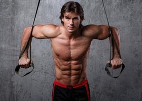 Muscular man during workout with suspension straps photo