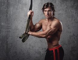 Muscular man during workout with suspension straps photo