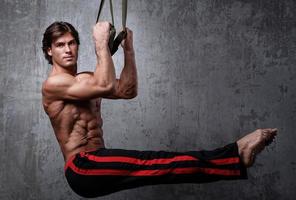 Muscular man during workout with suspension straps photo