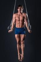 Strong and muscular gymnast guy on the rings photo