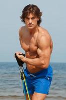 Guy working out with rubber band on the beach photo