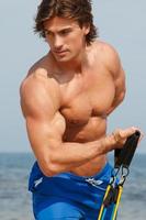 Guy working out with rubber band on the beach photo