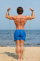 Guy working out with rubber band on the beach photo