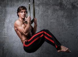 Muscular man during workout with suspension straps photo