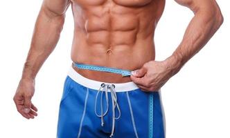 Bodybuilder measuring his waistline over white background photo