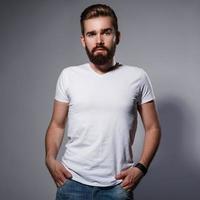 Stylish bearded man posing against gray background photo