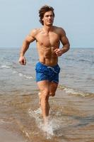 hombre durante el jogging por la costa del mar foto