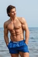 Muscular man during his workout on the beach photo