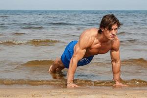 Muscular man during his workout on the beach photo