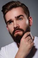 Portrait of young handsome bearded man in studio photo