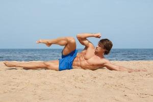 Muscular man during his workout on the beach photo