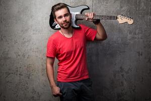 Guy with electric guitar beside concrete wall photo