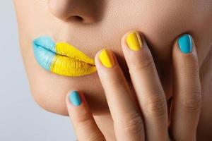 Female lips with two different lipsticks and colorful nails photo