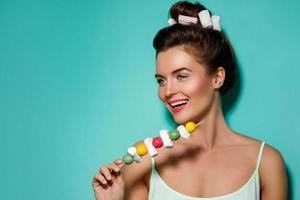 Happy woman with colorful makeup and sweet candies on skewer photo