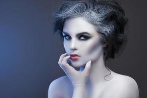Woman in white body-art in creative image of winter, snow queen, or another sad or evil character photo