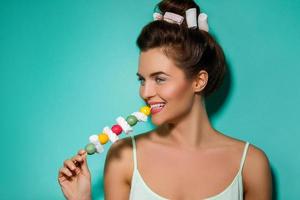 Happy woman with colorful makeup and sweet candies on skewer photo