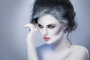 Woman in white body-art in creative image of winter, snow queen, or another sad or evil character photo