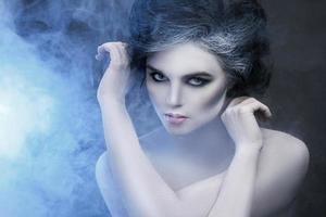 Woman in white body-art in creative image of winter, snow queen, or another sad or evil character photo