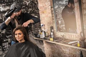 Hairdresser during work with beautiful woman client in salon photo