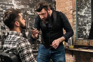 peluquero durante el trabajo con un cliente en la barbería foto