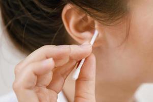 Woman cleaning ear with a cotton swab photo