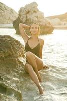 mujer en la playa con rocas al atardecer foto