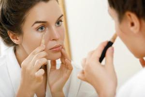 Woman using concealer for under eye circles photo