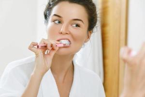 mujer cepillándose los dientes en el baño foto