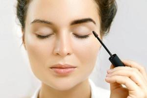 Beautiful woman is applying tinted eyebrow gel photo