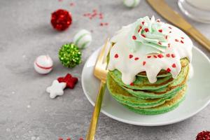 Green pancakes served with white glaze and whipped cream photo