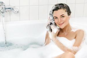 Woman is washing her hair with shampoo photo