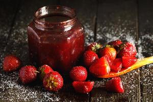 Homemade sweet strawberry jam on wooden table photo