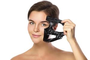 Beautiful woman is removing purifying mask from her face photo