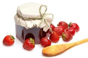 Jar of jam and strawberries on white background photo