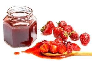 Jar of jam and strawberries on white background photo