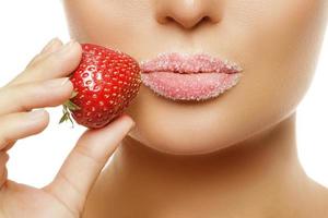 labios femeninos en azúcar y bayas de fresa foto