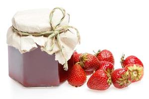Jar of jam and strawberries on white background photo