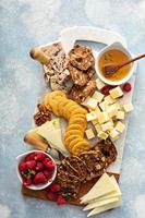 Cheese and snacks board with raspberry and crackers photo