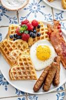 Breakfast table with waffles. fried egg, bacon and sausage