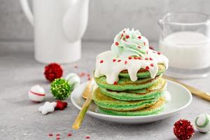 Green pancakes served with white glaze and whipped cream photo