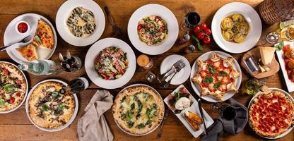 gran mesa con comida italiana, pizzas y pastas foto