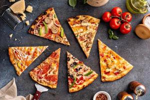 Variety of pizza slices top view on dark background photo