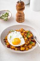 Potato, onion and ham hash topped with fried egg photo