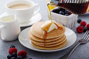 Stack of pancakes with butter and syrup pouring over photo