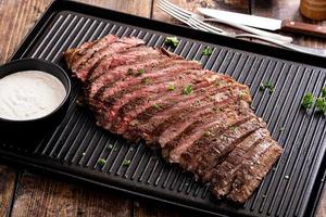 Grilled flank steak with horseradish sauce on a grill pan photo