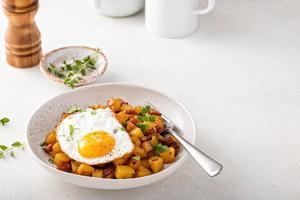 Potato, onion and ham hash topped with fried egg photo