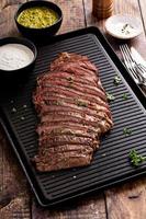 Grilled flank steak with chimichurri sauce on a grill pan photo